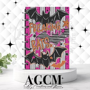 May include: A disc-bound notebook featuring a vertical striped background in hot pink and white. The cover displays three black bats, orange stars, and smaller pink and orange bats. The text "FREAKING BATS" is printed in large orange letters.