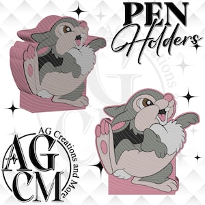Könnte beinhalten: Stifthalter mit einem Cartoon-Hasen-Design in Grau, Rosa und Weiß. Die Stifthalter haben einen 3D-Effekt und sind mit dem Text "PEN Holders" verziert. Das Logo "AG Creations and More" ist ebenfalls sichtbar.