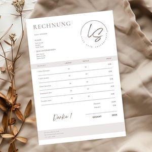May include: A white invoice with the word "RECHNUNG" at the top, featuring a logo and itemized list. The document is on a beige fabric background with dried floral accents. The invoice includes a "Danke!" signature.