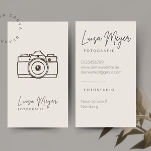 May include: A white business card with black text and a line drawing of a camera. The text reads "Luisa Meyer Fotografie" and includes contact information and the address of the photography studio.