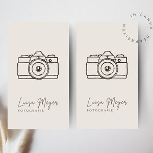May include: Two cream-coloured business cards with a black line drawing of a camera and the text "Louisa Meyer Fotografie" on each card.