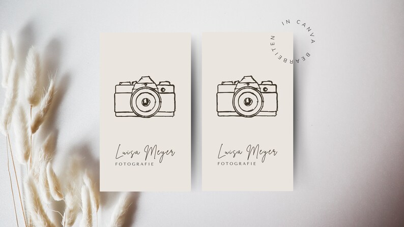 May include: Two cream-coloured business cards with a black line drawing of a camera and the text "Louisa Meyer Fotografie" on each card.