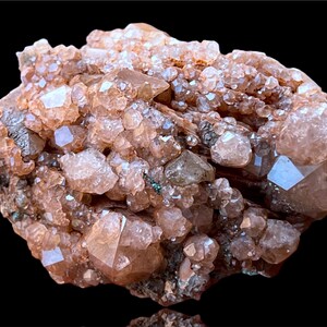 May include: A cluster of pink and brown crystals with a rough, natural texture. The crystals are densely packed together, creating a visually interesting and unique piece.