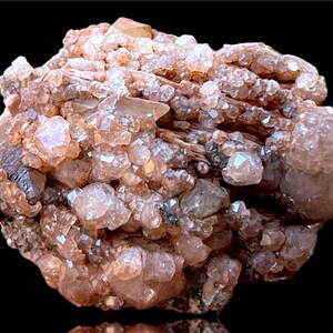 May include: A cluster of pink and brown crystals with a rough, natural texture. The crystals are densely packed together, creating a visually interesting and unique piece.
