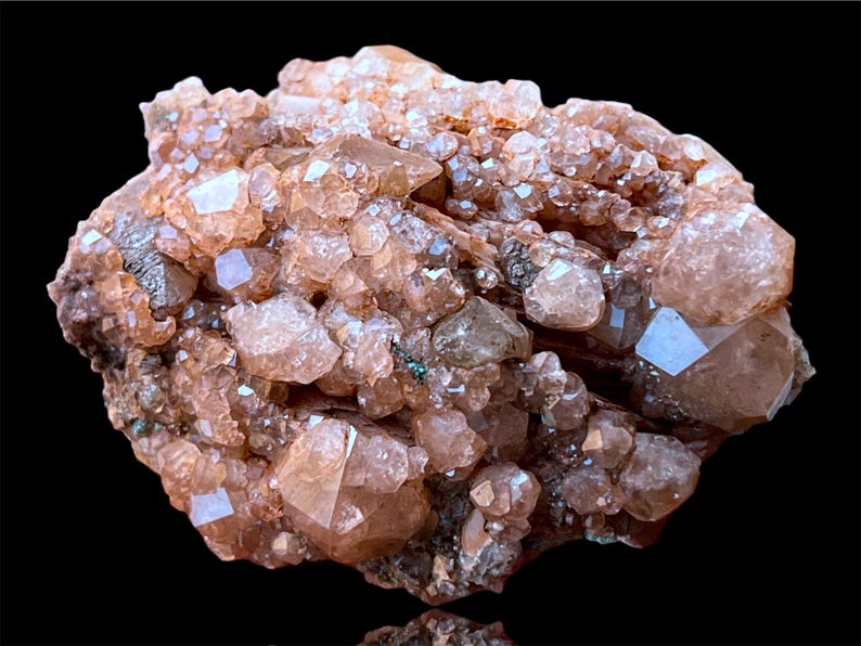May include: A cluster of pink and brown crystals with a rough, natural texture. The crystals are densely packed together, creating a visually interesting and unique piece.