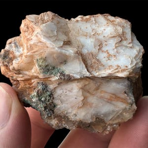 May include: A rough, white and brown rock with a layered, flaky texture. The rock has a green mineral deposit on one side.