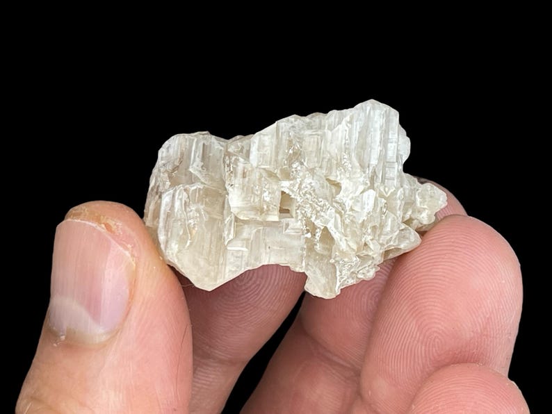 May include: A cluster of translucent, white, naturally formed crystals with a rough, textured surface.