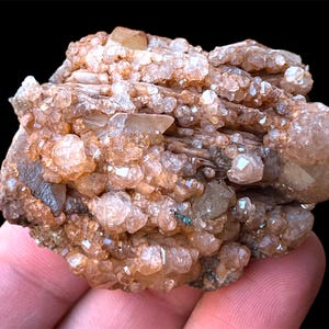 May include: A cluster of light brown and clear quartz crystals on a matrix of brown and gray rock. The crystals are clustered together in a dense formation, with some of the crystals having a more pointed shape than others.