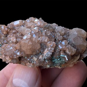May include: A cluster of brown and clear quartz crystals on a matrix of dark brown and green rock. The crystals are translucent and have a glassy luster.