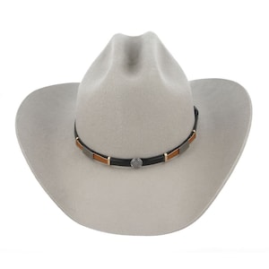 Pode incluir: Um chap&eacute;u de cowboy de feltro cinza claro com uma faixa de couro preta e detalhes marrons. A faixa tem uma concha de prata.