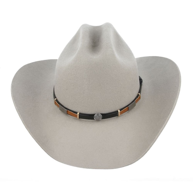 Pode incluir: Um chap&eacute;u de cowboy de feltro cinza claro com uma faixa de couro preta e detalhes marrons. A faixa tem uma concha de prata.