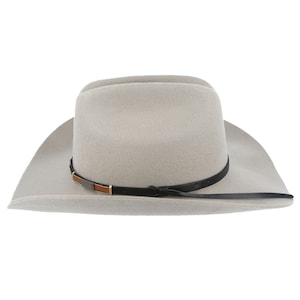 Pode incluir: Um chap&eacute;u de cowboy de feltro cinza claro com uma faixa de couro preto e um detalhe de couro castanho. O chap&eacute;u tem uma aba larga e uma coroa alta.