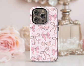 May include: A pink and white phone case with a pattern of pink bows and hearts. The case is designed for an iPhone 14 Pro.