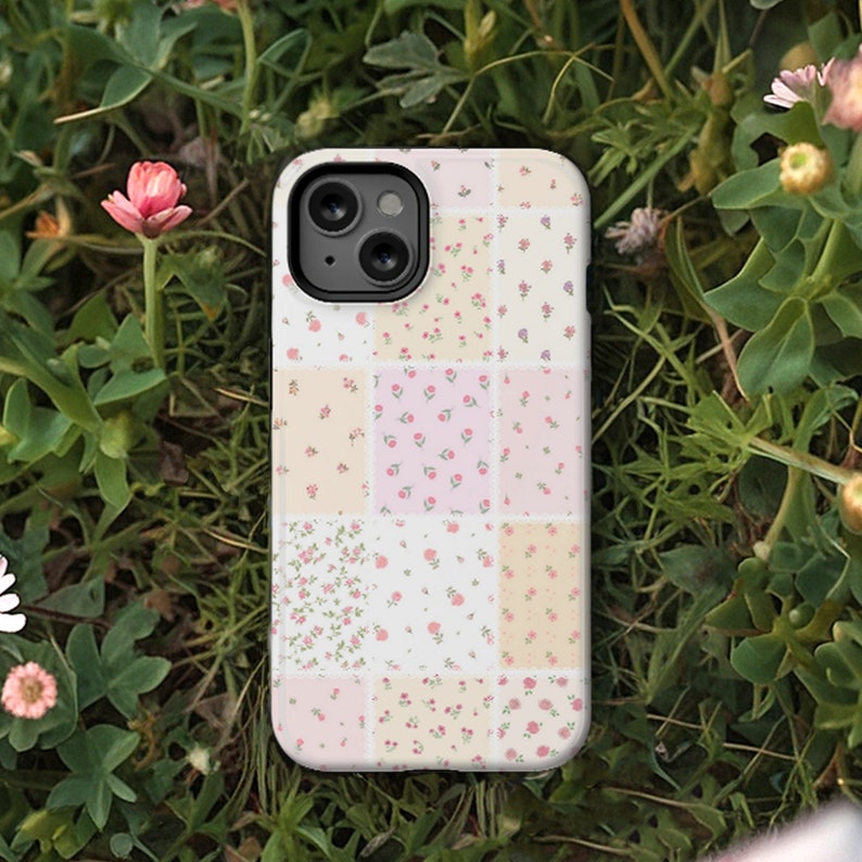 Op de afbeelding: Een witte telefoonhoes met een patchwork-ontwerp met verschillende kleine bloemenpatronen in roze, geel en wit.