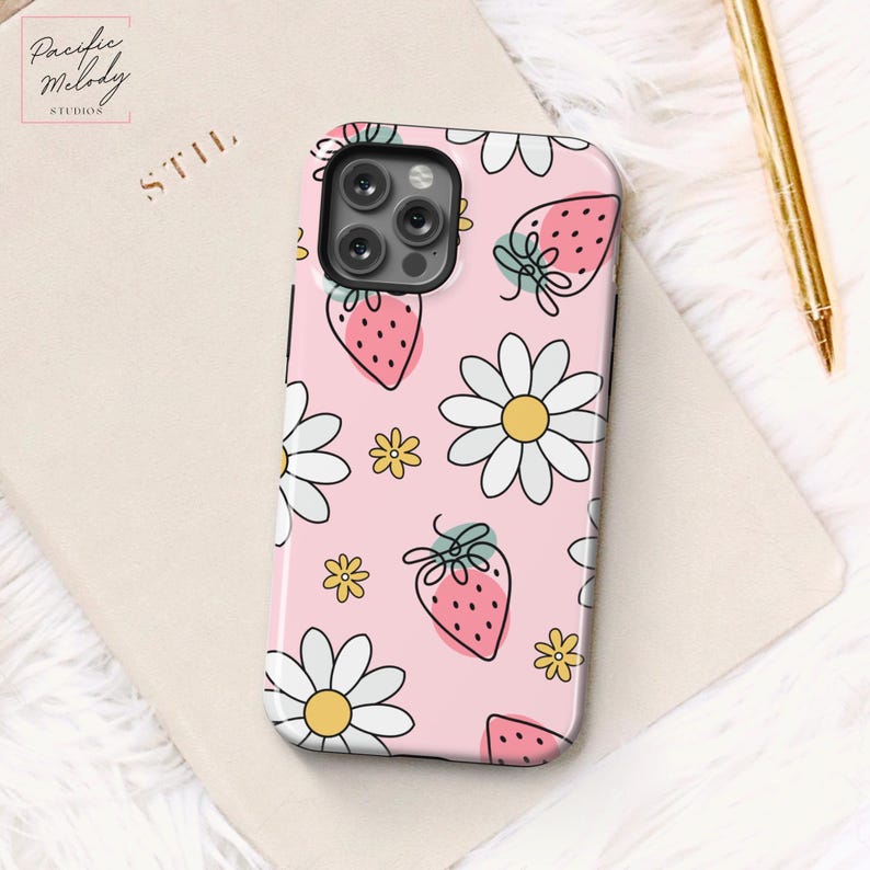 May include: A pink phone case with a white daisy and strawberry pattern. The case has a cutout for the camera lens.