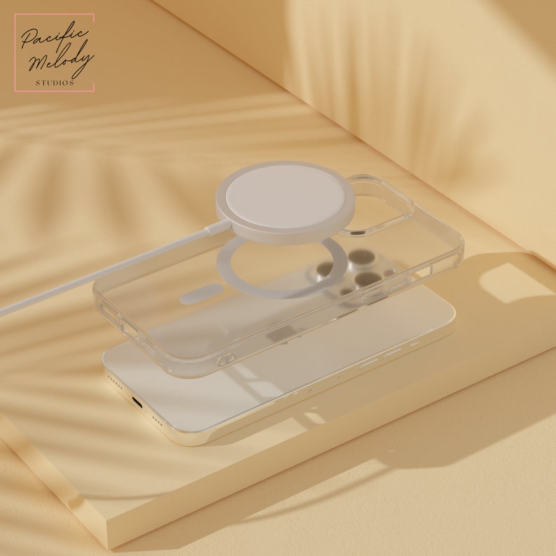 May include: A clear phone case with a white wireless charging pad on top of it. The phone case is on top of a white phone. The phone and case are on a light brown surface.
