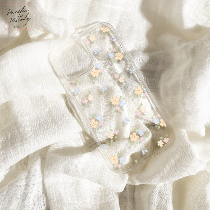 May include: A clear phone case with a floral pattern. The flowers are in shades of blue, pink, and yellow. The case is designed for an iPhone.