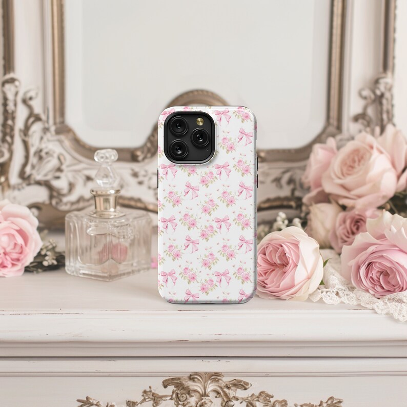 May include: A white phone case with a pink floral pattern and a black camera lens.