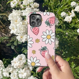 May include: A pink phone case with a white daisy and strawberry pattern.