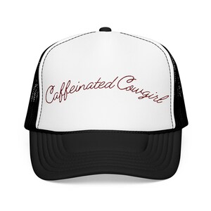 May include: A black and white trucker hat with the text "Caffeinated Cowgirl" in a cursive font. The hat has a white front panel and a black brim and mesh back.