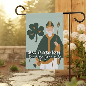 May include: A green and blue garden flag with a cartoon illustration of St. Patrick holding a staff. The flag reads "St. Patrick pray for us".
