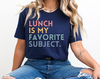 May include: A navy blue t-shirt with the text "LUNCH IS MY FAVORITE SUBJECT." in a rainbow gradient.