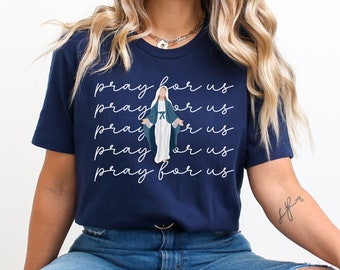 May include: A navy blue t-shirt with a white graphic of the Virgin Mary and the text "pray for us" repeated five times.