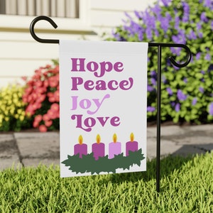 May include: White garden flag with the words "Hope Peace Joy Love" in pink and purple lettering. The flag also features a green wreath with four purple candles.