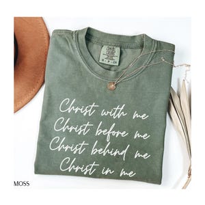 May include: A green t-shirt with the text "Christ with me, Christ before me, Christ behind me, Christ in me" printed in white.