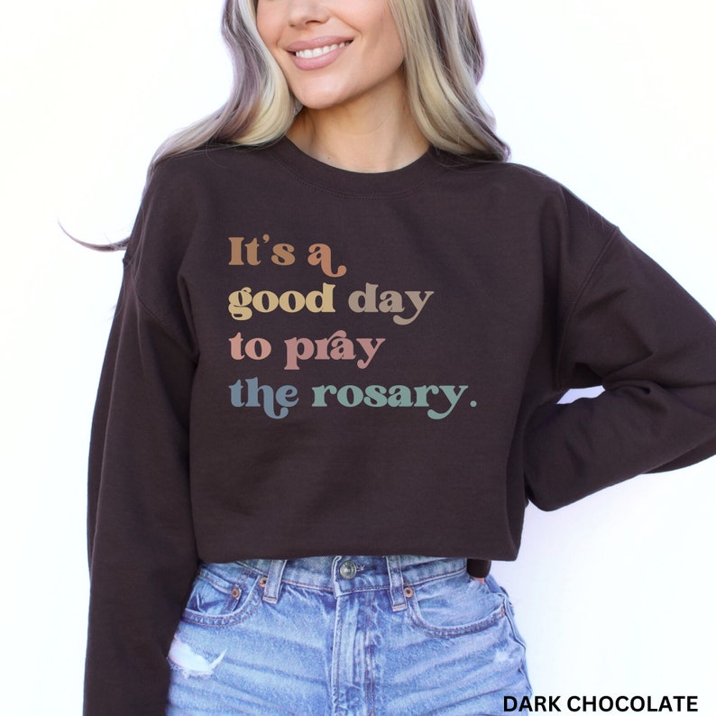 May include: A brown sweatshirt with the text "It's a good day to pray the rosary." printed in rainbow colors.