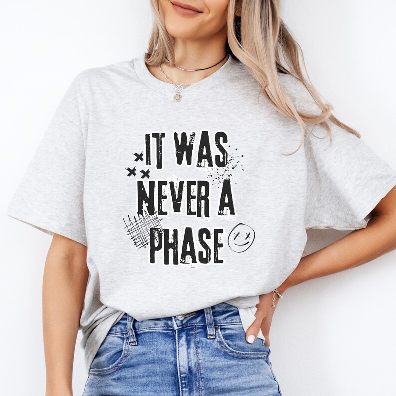 Może przedstawiać: Szary T-shirt z napisem "It was never a phase" w kolorze czarnym w stylu graficznym z efektem zużycia.