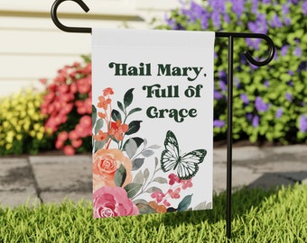May include: A white garden flag with a floral design and a butterfly. The text on the flag reads "Hail Mary, Full of Grace".