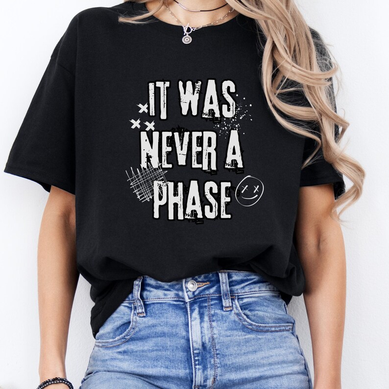 Może przedstawiać: Czarny T-shirt z białym napisem "It was never a phase" i uśmiechniętą buźką.