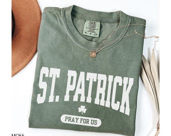 May include: A green t-shirt with the text "St. Patrick Pray for Us" in white. The shirt has a distressed look and features a shamrock graphic.