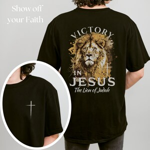 May include: Black t-shirt with a lion graphic and the text "Victory in Jesus, The Lion of Judah". The front of the shirt has a small white cross.