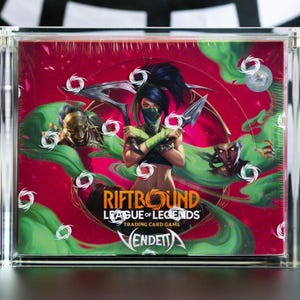 May include: A sealed Riftbound League of Legends trading card game box in a clear acrylic display case. The box features a central character with dark hair and green accents, surrounded by swirling green smoke, gold text, and white circular icons.