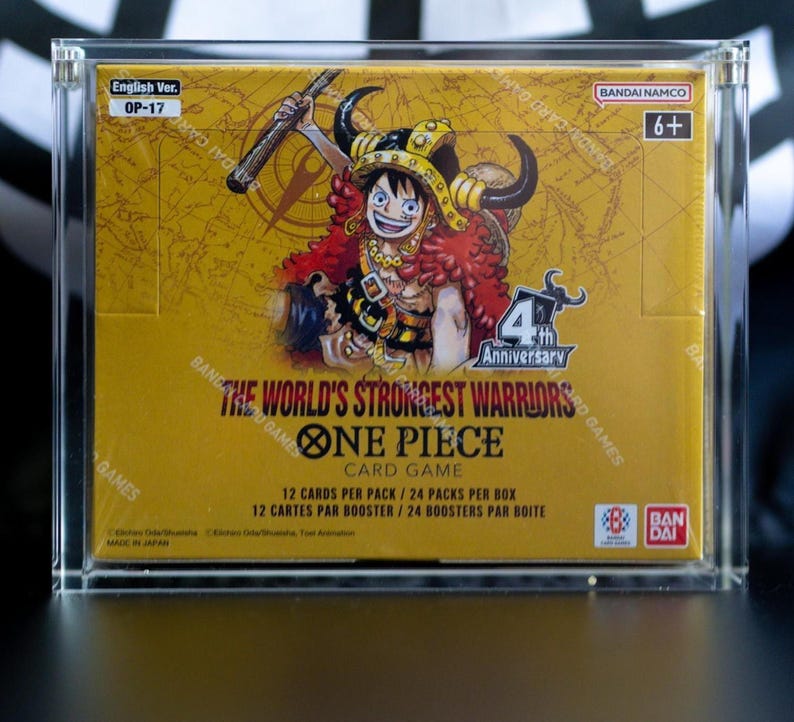 May include: A sealed One Piece Card Game booster box, The World's Strongest Warriors OP-17, encased in a clear acrylic display. The yellow box features an illustration of a character with a horned helmet, the 4th Anniversary logo, and Bandai branding.