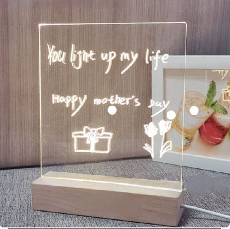 K&ouml;nnte beinhalten: Ein wei&szlig;es, leuchtendes Acrylschild mit dem Text "You light up my life Happy Mother's Day" und einer Zeichnung einer Geschenkbox und zwei Blumen.