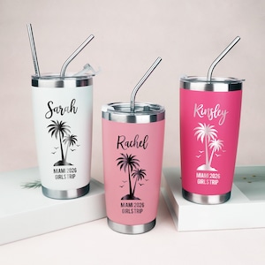 Könnte beinhalten: Drei Edelstahlbecher mit Deckeln und Metallstrohhalmen. Der weiße Becher trägt den Namen Sarah, der rosa Becher Rachel und der magentafarbene Becher Kinsley. Jeder hat eine Palmen-Grafik und den Text Miami 2026 Girls Trip.