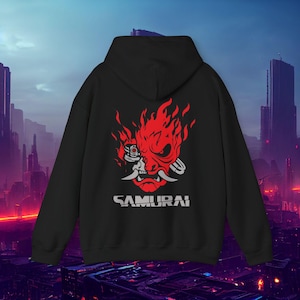 Może przedstawiać: Czarna bluza z kapturem z czerwono-białą grafiką maski samuraja w płomieniach. Słowo "SAMURAI" jest wydrukowane na dole na biało. Tło przedstawia futurystyczne miasto.