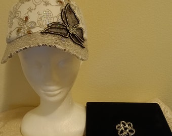 Casquette florale blanche avec motifs floraux en strass et motifs circulaires en fil de fer. Plus une broche en argent chic.