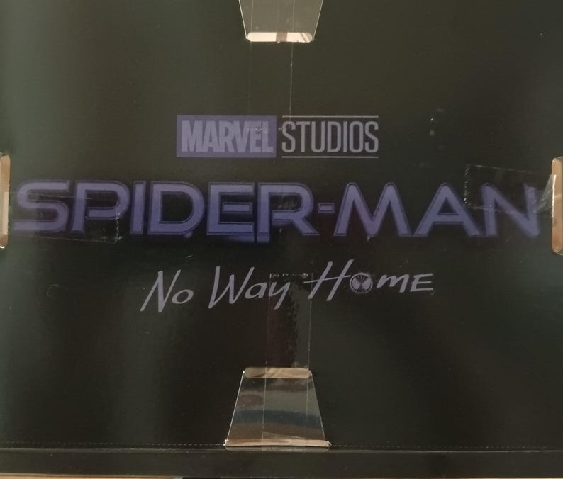 May include: A black and white image of the Marvel Studios logo with the text "Spider-Man No Way Home" in blue lettering.