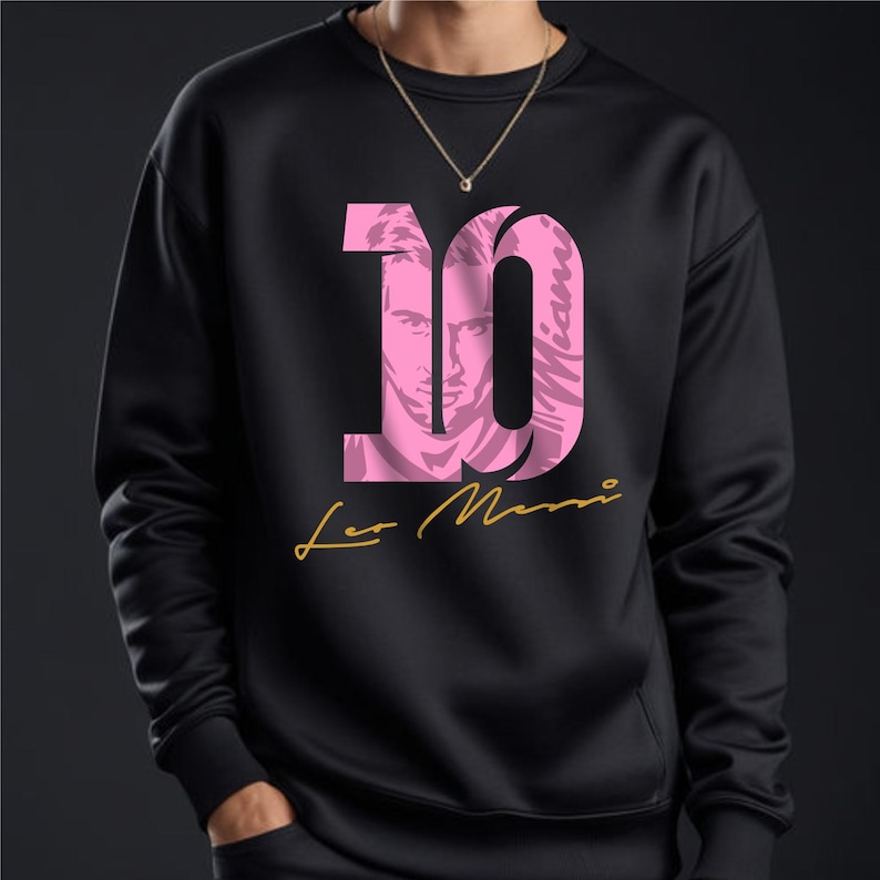 May include: Black sweatshirt with a pink number 10, featuring a silhouette of a person's face inside the number. The text "Leo Messi" is written in gold below the number.