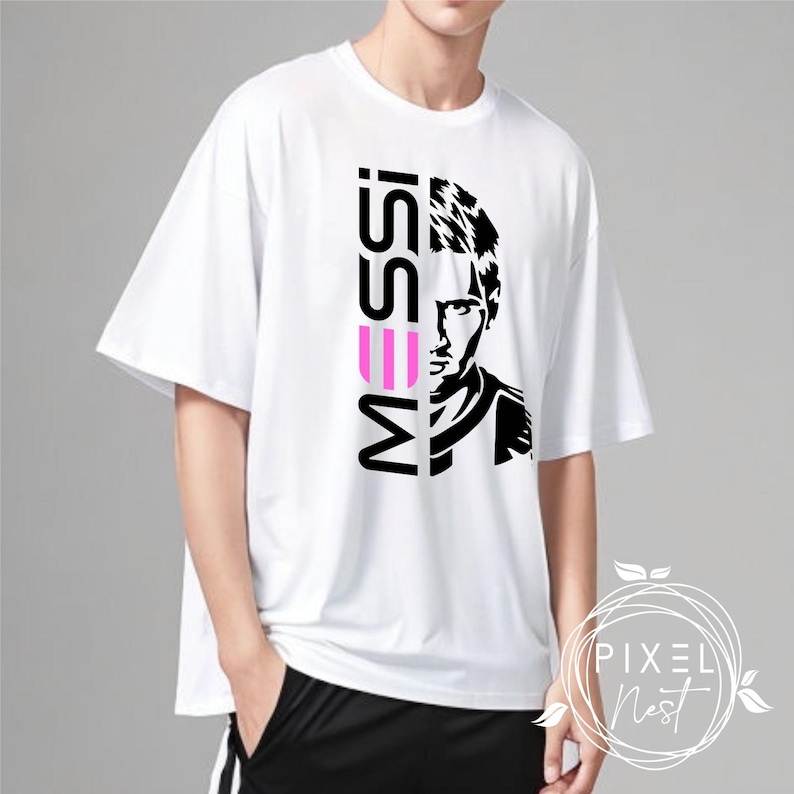 May include: White t-shirt with a black and white graphic of a man's face and the word "MESSI" in pink and black letters.