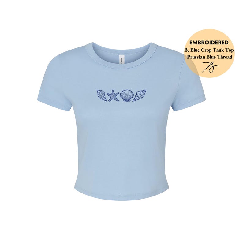 May include: A light blue crop top with embroidered seashells and a starfish design. The shirt has short sleeves and a crew neck. The text on the tag says "EMBROIDERED B. Blue Crop Tank Top Prussian Blue Thread".