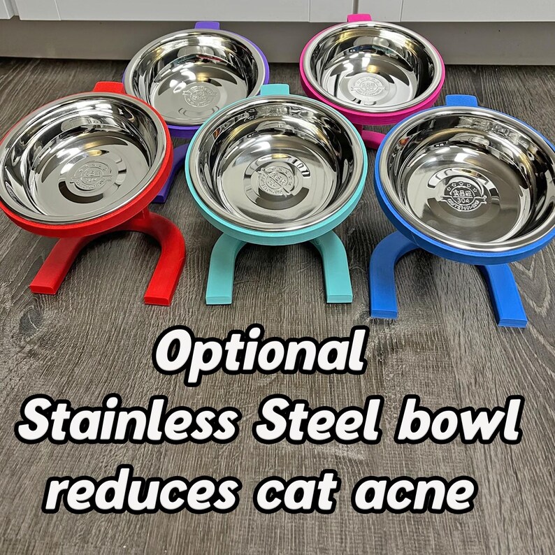 May include: A selection of elevated stainless steel pet bowls in red, purple, teal, pink, and blue. Each bowl is supported by a stand of the same colour. The image includes the text: "Optional Stainless Steel bowl reduces cat acne."