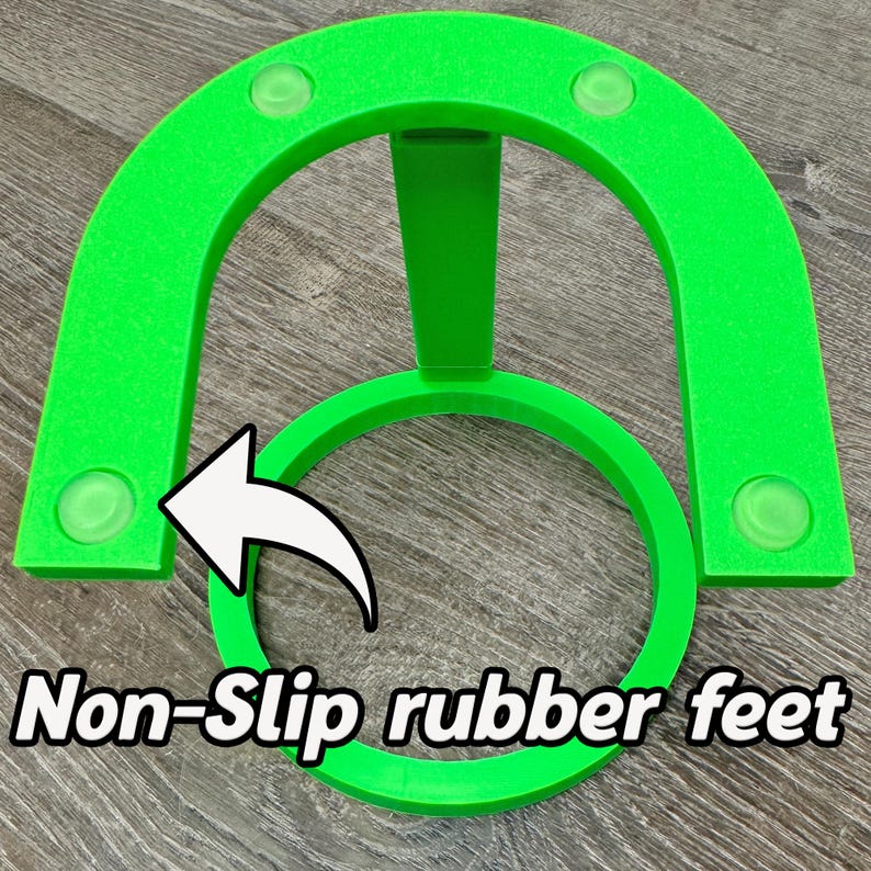 May include: Bright green, U-shaped object with a circular base and a central support. The object has four clear, non-slip rubber feet. The text "Non-Slip rubber feet" is displayed in a white, outlined font.