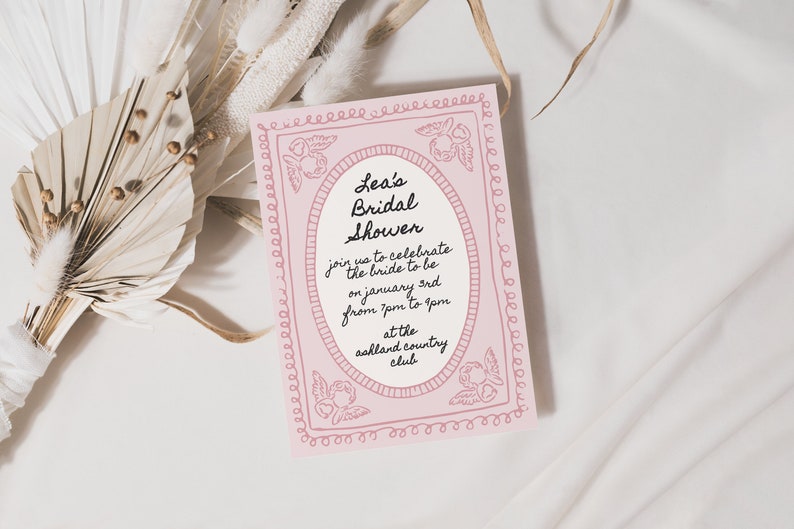 Pode incluir: Um convite rosa para um ch&aacute; de panela com uma borda decorativa e o texto "Lea's Bridal Shower" em fonte cursiva preta. O convite detalha a data, hora e local do evento.