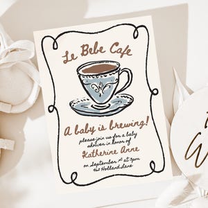 May include: A baby shower invitation with the text "Le Bebe Cafe" and "A baby is brewing!" features a cup of coffee. The invitation is accompanied by a pair of white baby shoes and a wooden sign that says "Hello World".