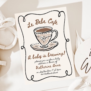 May include: A baby shower invitation with the text "Le Bebe Cafe" and "A baby is brewing!" in brown ink. The invitation features a drawing of a teacup and saucer. White baby shoes and a decorative sign that says "Hello World" are also in the image.